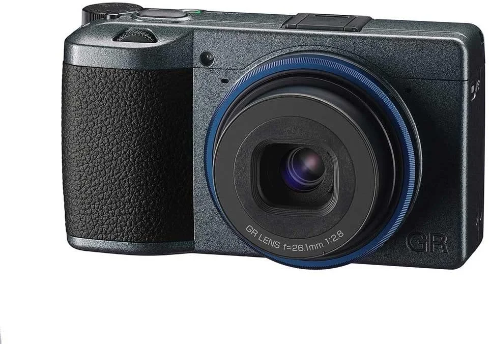 دوربین دیجیتال کامپکت Ricoh GR IIIx Urban Edition، بدنه خاکستری متالیک با حلقه آبی سرمه ای، دارای سنسور CMOS با سایز APS-C 24 مگاپیکسلی، لنز 40mmF2.8 GR (در فرمت 35 میلی متری)