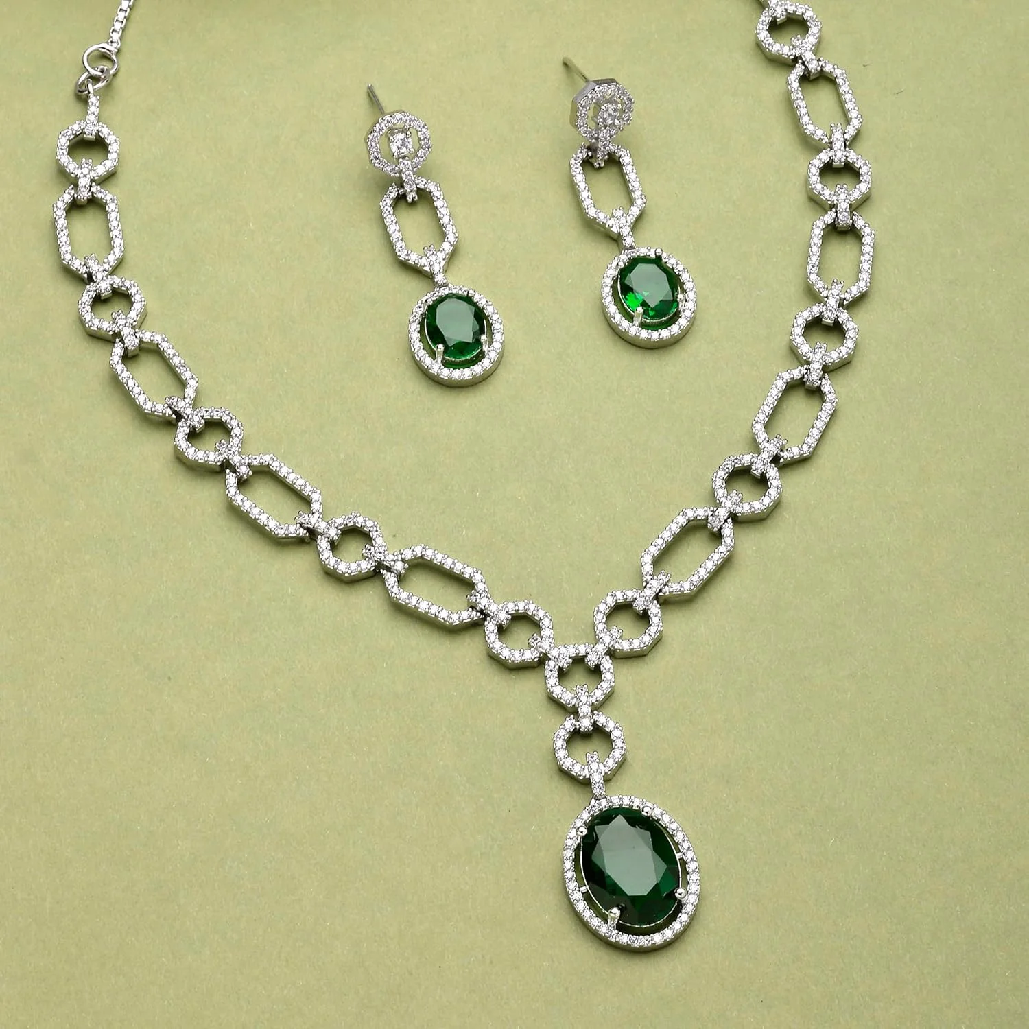 ست جواهرات زنانه شامل گردنبند و گوشواره با روکش رودیوم، طرح نقره ای، نگین های اتمی سبز رنگ و جزئیات مدرن از برند زنم ست جواهرات زنانه شامل گردنبند و گوشواره با روکش رودیوم، طرح نقره ای، نگین های اتمی سبز رنگ و جزئیات مدرن از برند زنم