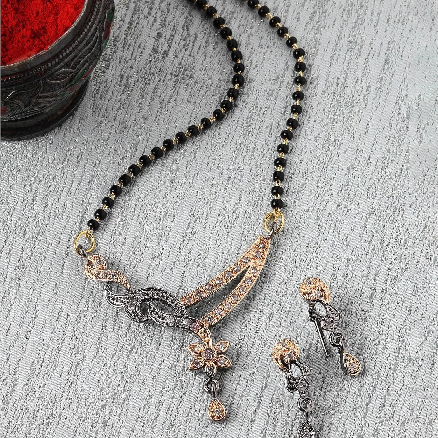 نیم ست مانگالسوترای رزگلد و دودی رنگ زنانه و دخترانه زنمه، مزین به سنگ های مصنوعی و مهره های مشکی به همراه گوشواره، سایز آزاد، روکش رزگلد، سنگ های مصنوعی و مهره