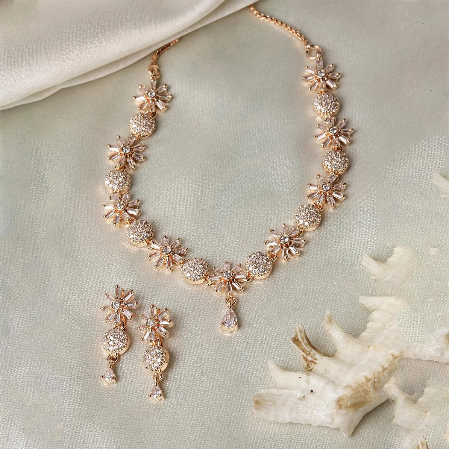 ست گردنبند و گوشواره زنانه طرح گل با نگین های اتمی سفید و روکش رزگلد برند زنمی ست گردنبند و گوشواره زنانه طرح گل با نگین های اتمی سفید و روکش رزگلد برند زنمی