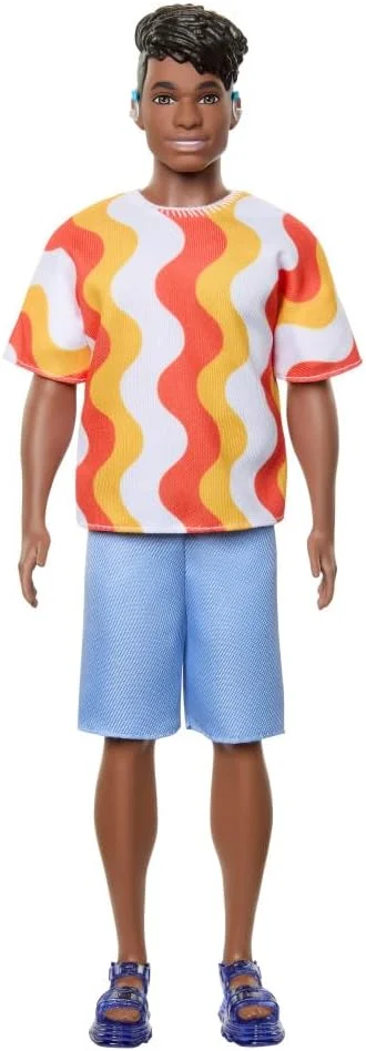 عروسک کن فشنista شماره 220 با سمعک پشت گوش و اندام درشت، با پیراهن طرح دار نارنجی، شورت و صندل ژله ای قابل تعویض