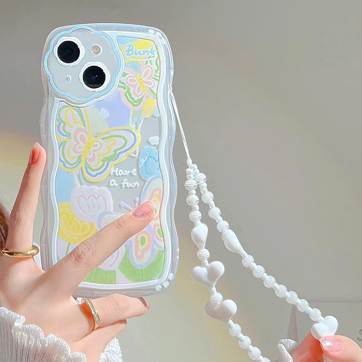 کاور محافظ آیفون 14 با طرح پروانه و گل کارتونی زیبا به همراه بند مچی مهره دار قلبی، جنس TPU نرم و محافظ کامل - طرح پروانه