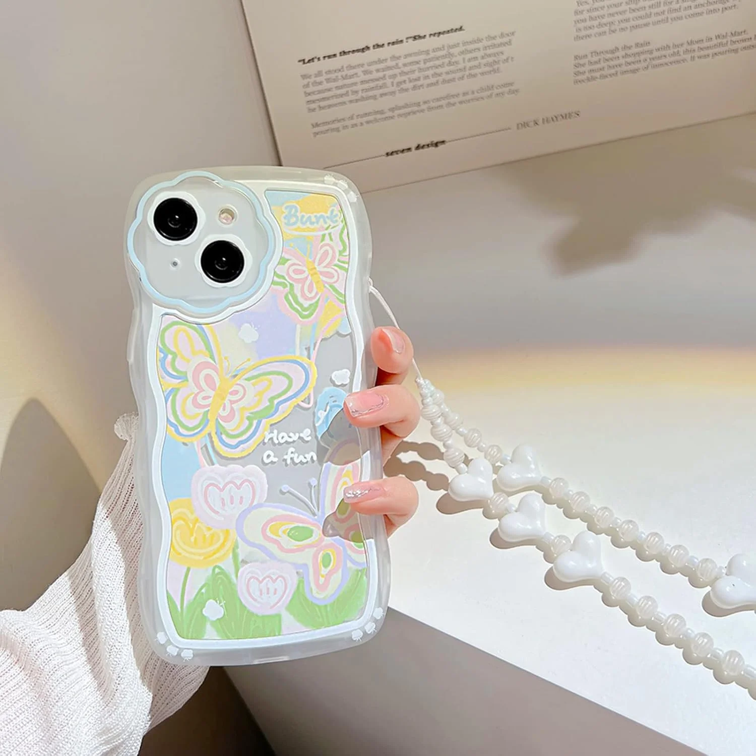 کاور محافظ آیفون 14 با طرح پروانه و گل کارتونی زیبا به همراه بند مچی مهره دار قلبی، جنس TPU نرم و محافظ کامل - طرح پروانه