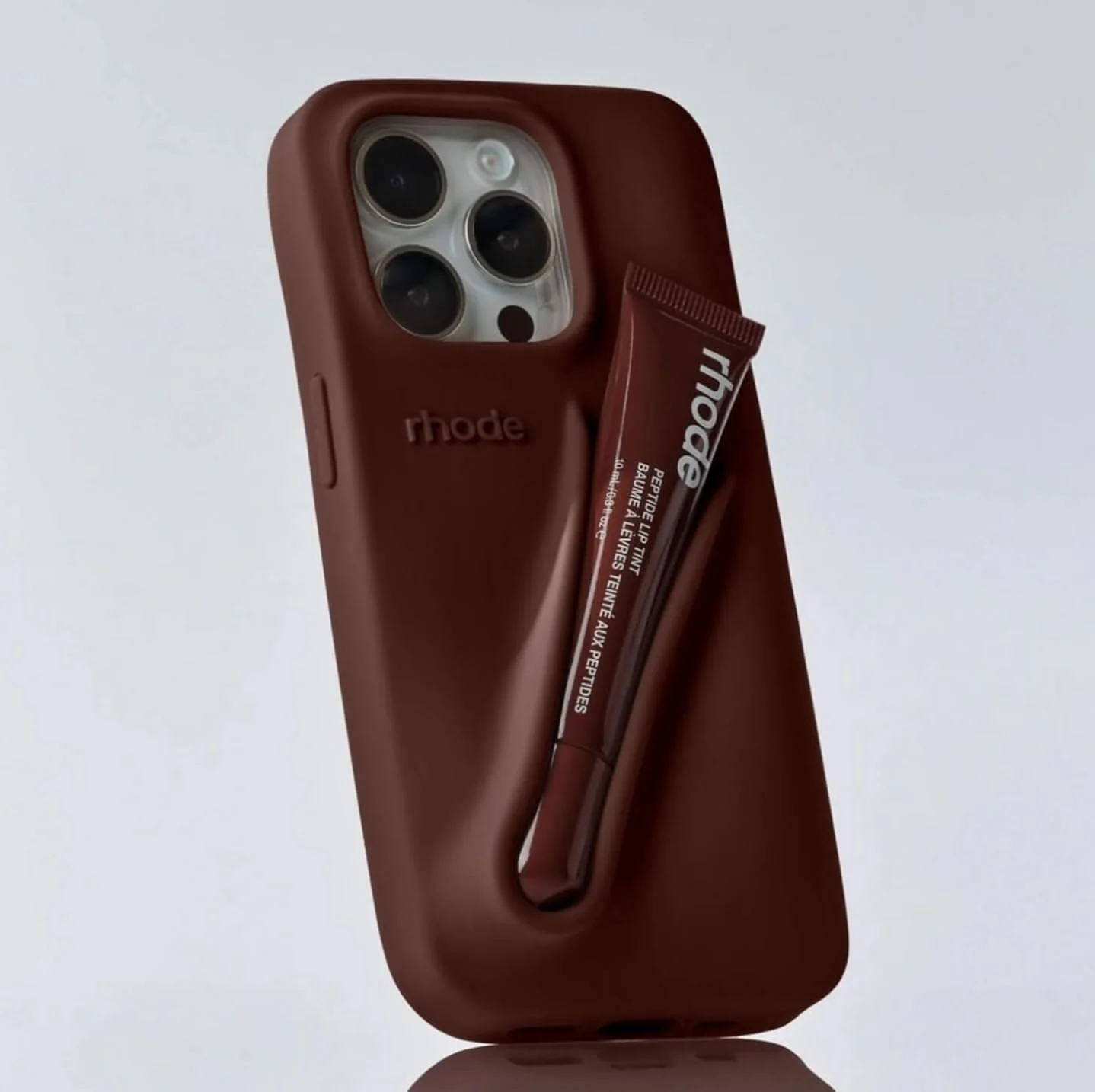 قاب گوشی چند منظوره مدل کیف مسافرتی سیلیکونی شیک (قهوه ای) سازگار با آیفون 16 پرو مکس به همراه جای بالم لب در بسته بندی اصلی