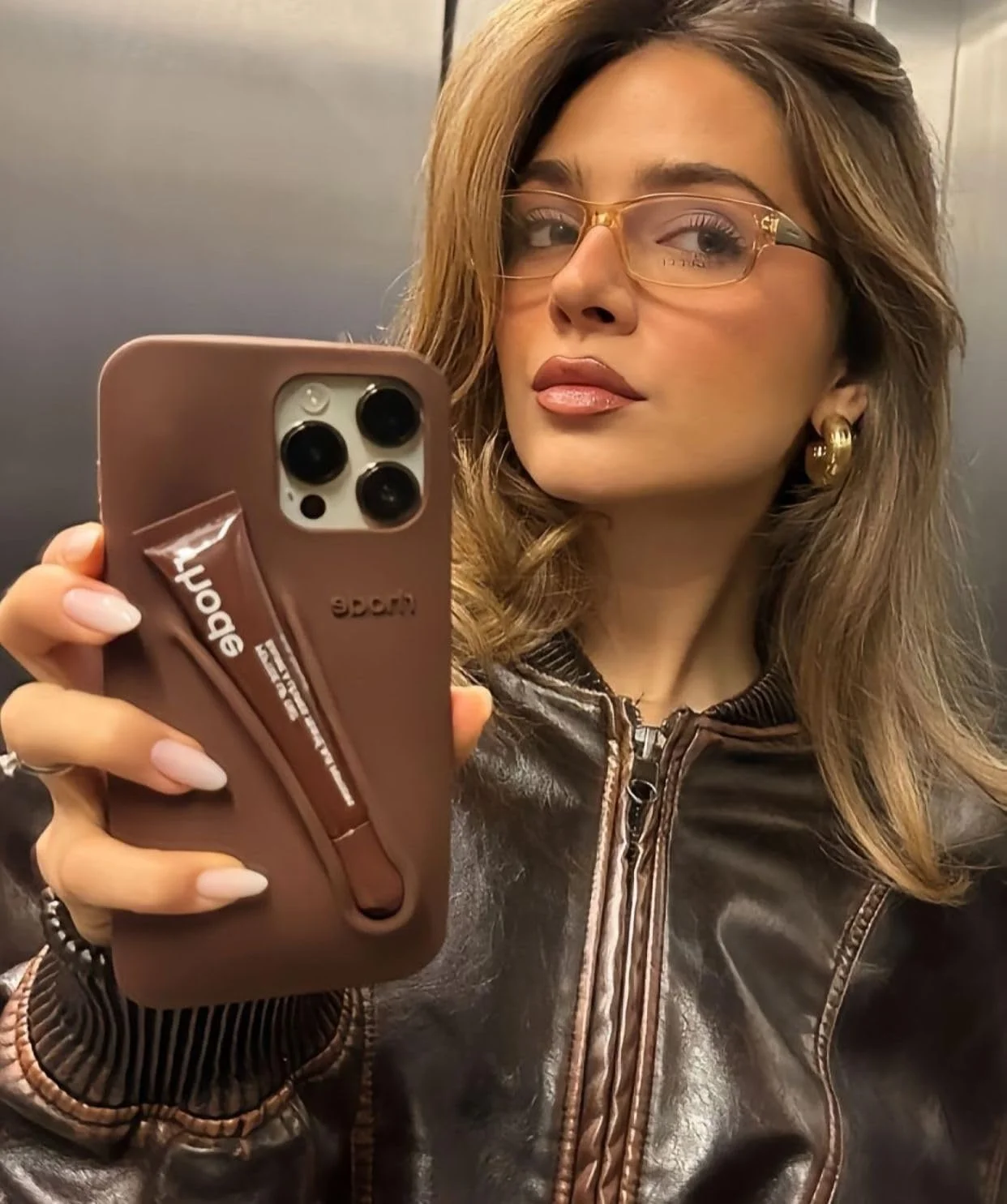 قاب گوشی چند منظوره مدل کیف مسافرتی سیلیکونی شیک (قهوه ای) سازگار با آیفون 16 پرو مکس به همراه جای بالم لب در بسته بندی اصلی