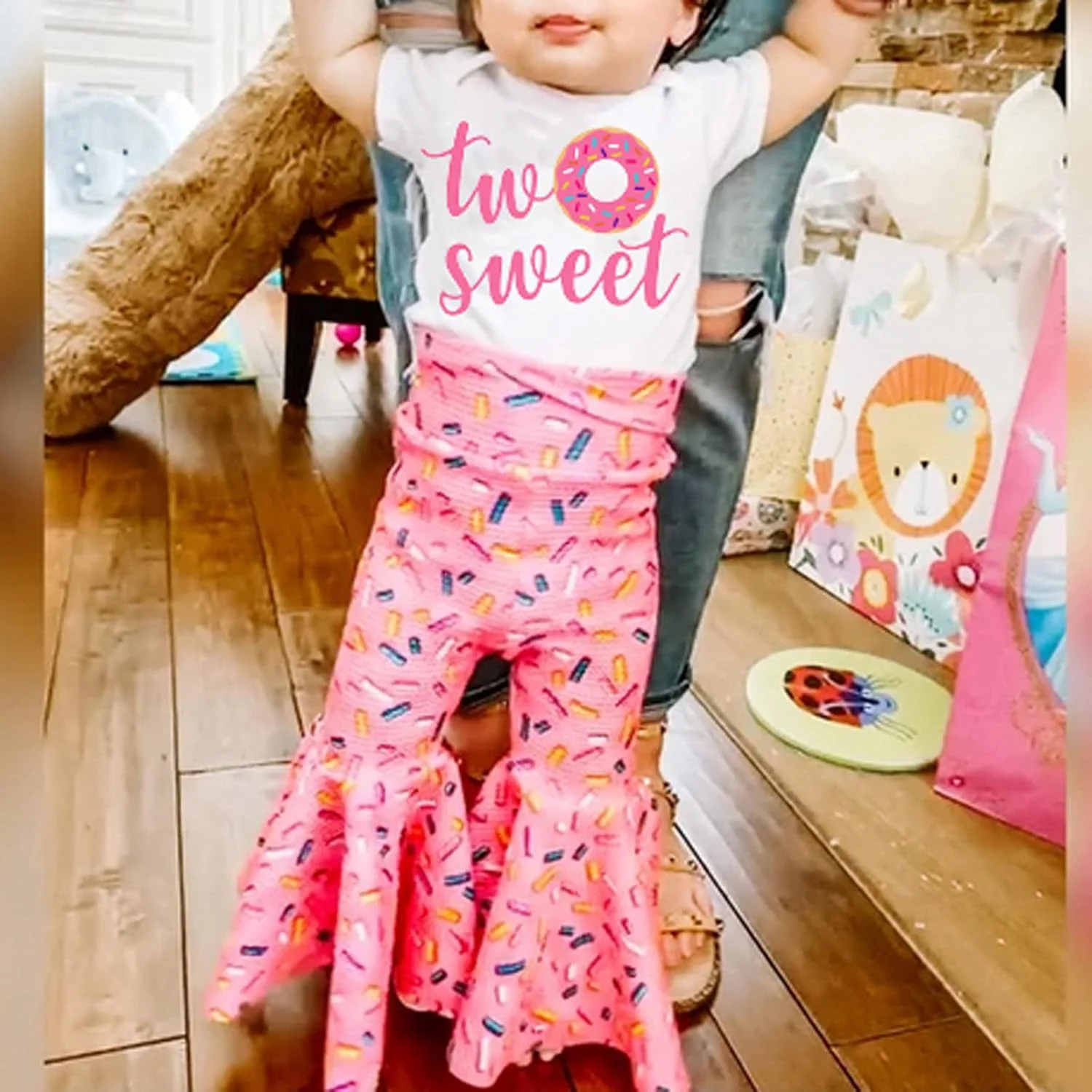 ست لباس تولد دخترانه شامل تیشرت آستین بلند، شلوار دمپا گشاد طرح دونات و هدبند