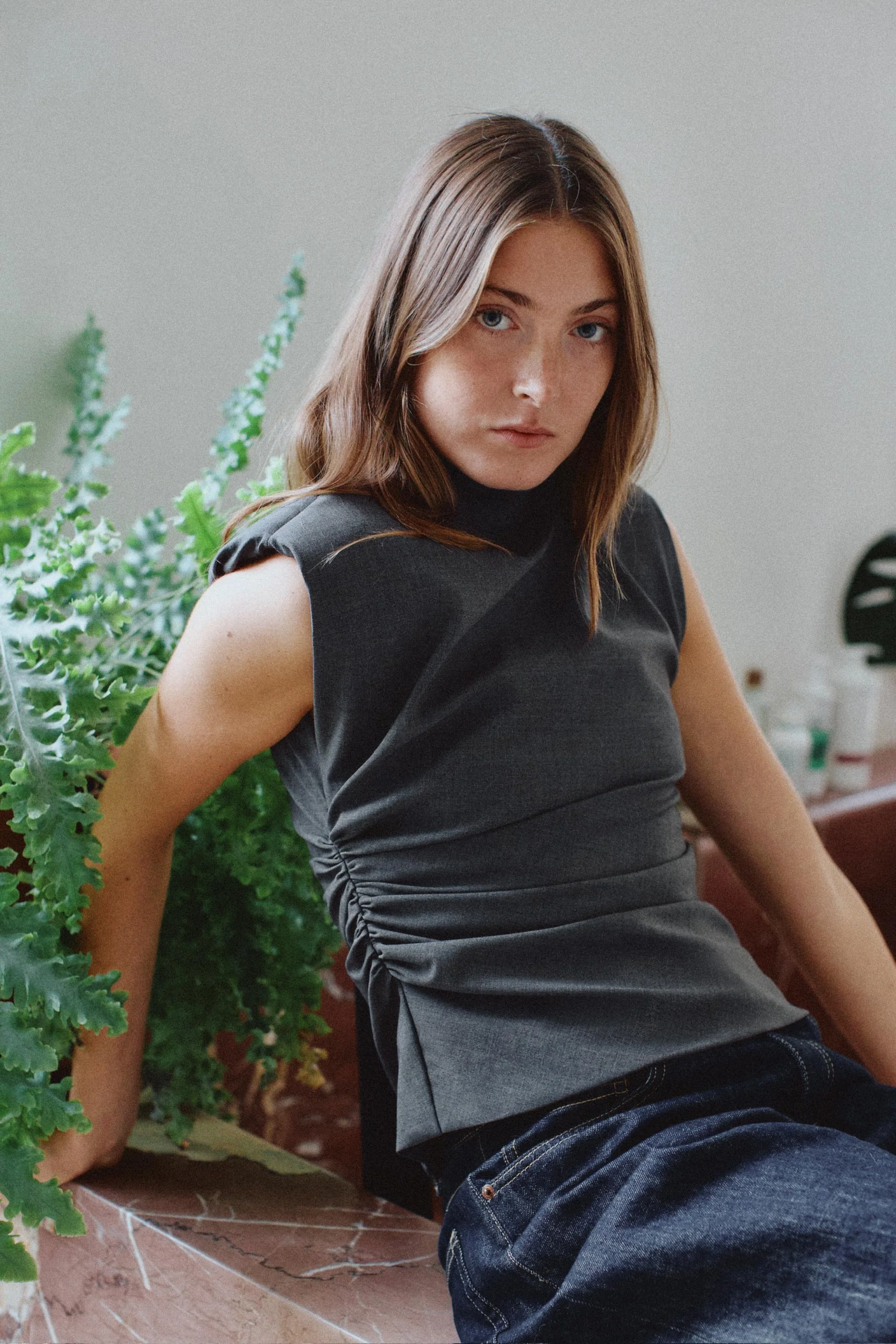 تاپ یقه ایستاده با بند. مدل آستین حلقه ای با پدهای سرشانه. دارای جزئیات چین دار در قسمت پهلو.