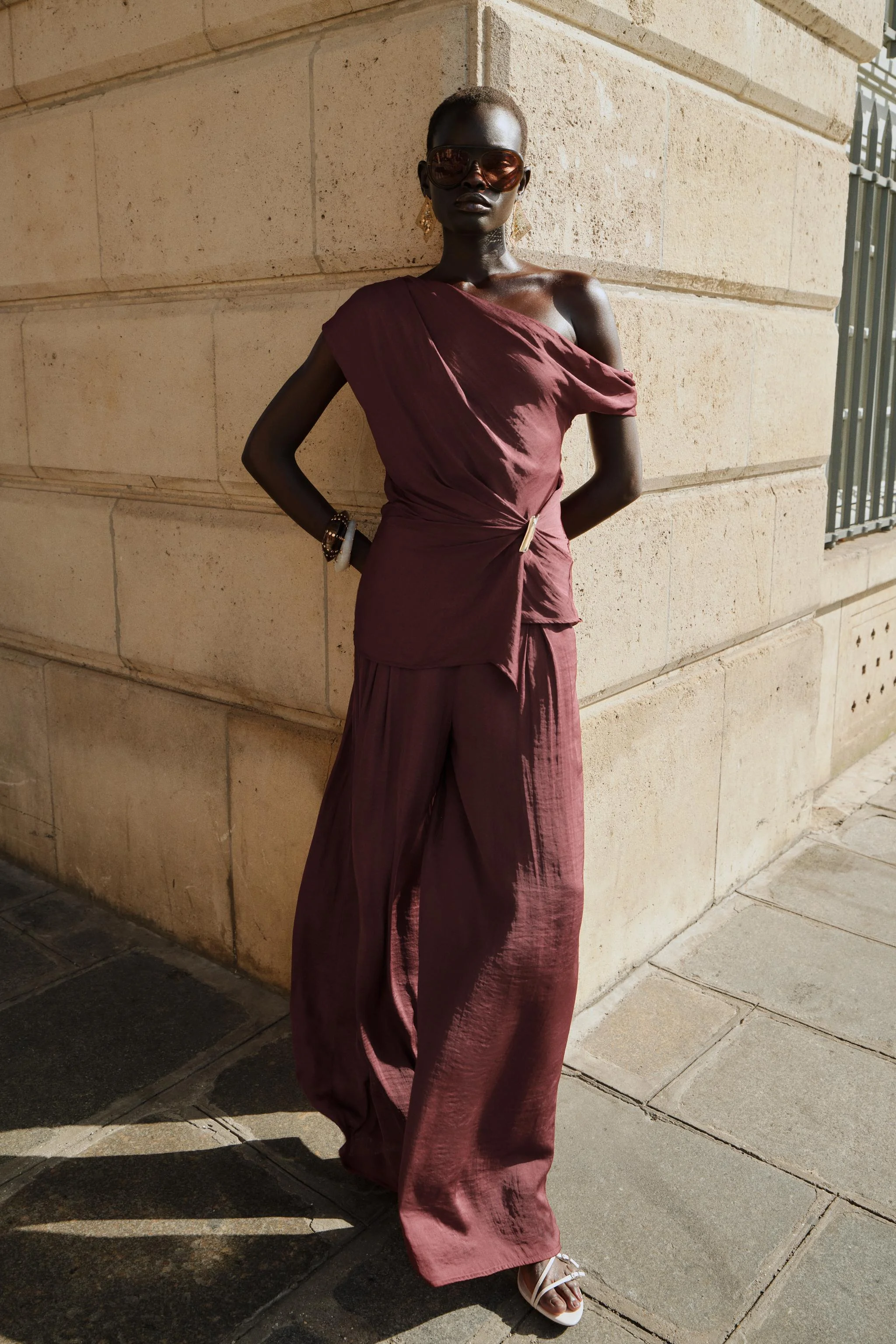 تاپ یقه روان با آستین های نامتقارن. جزئیات سخت افزاری طلایی رنگ در قسمت جلو.