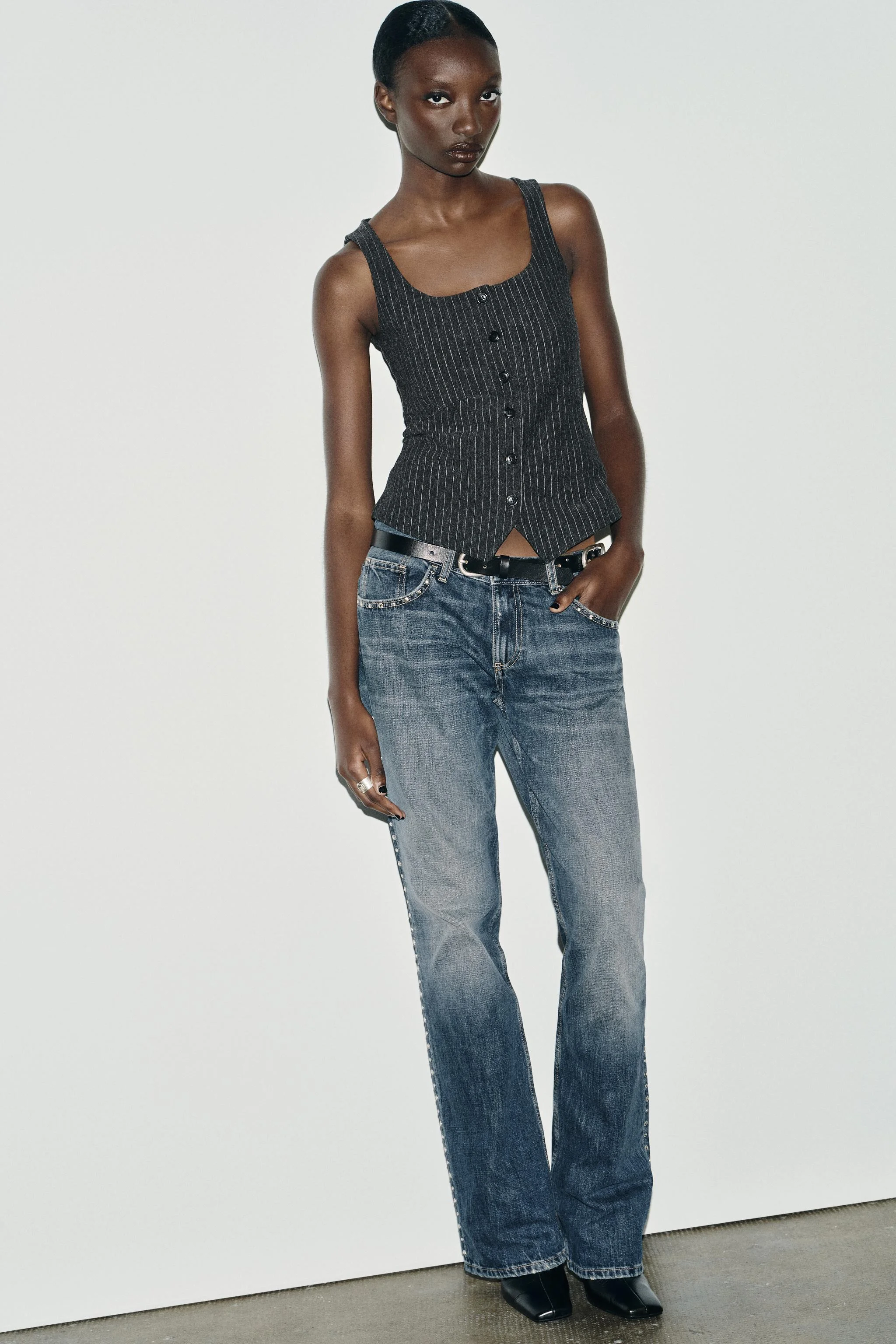 تاپ راه راه با یقه گرد و طراحی بدون آستین. دارای دکمه در قسمت جلوی لباس.