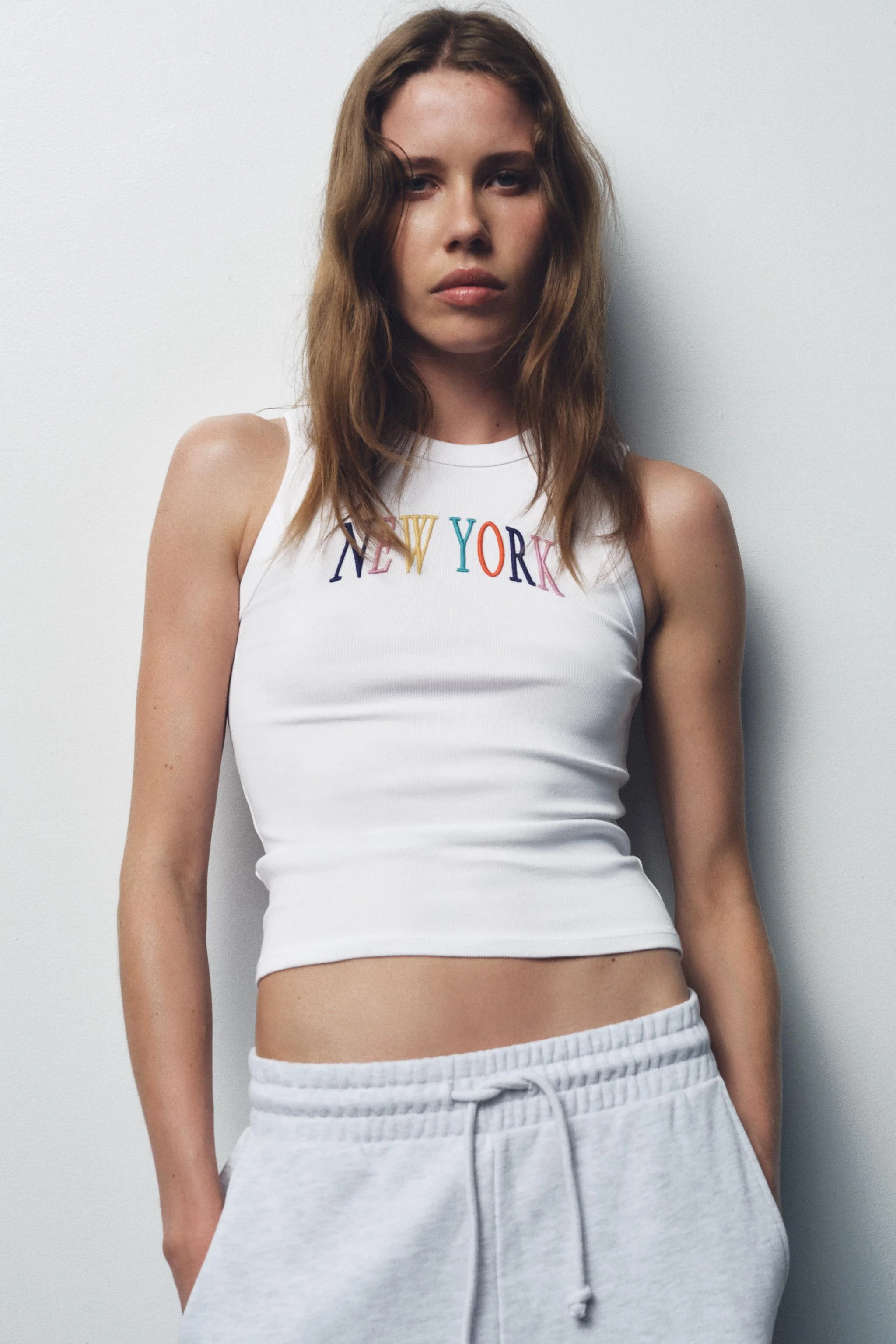 تاپ یقه گرد با طرح آستین حلقه ای. دارای جزئیات شعار گلدوزی شده در قسمت جلو.