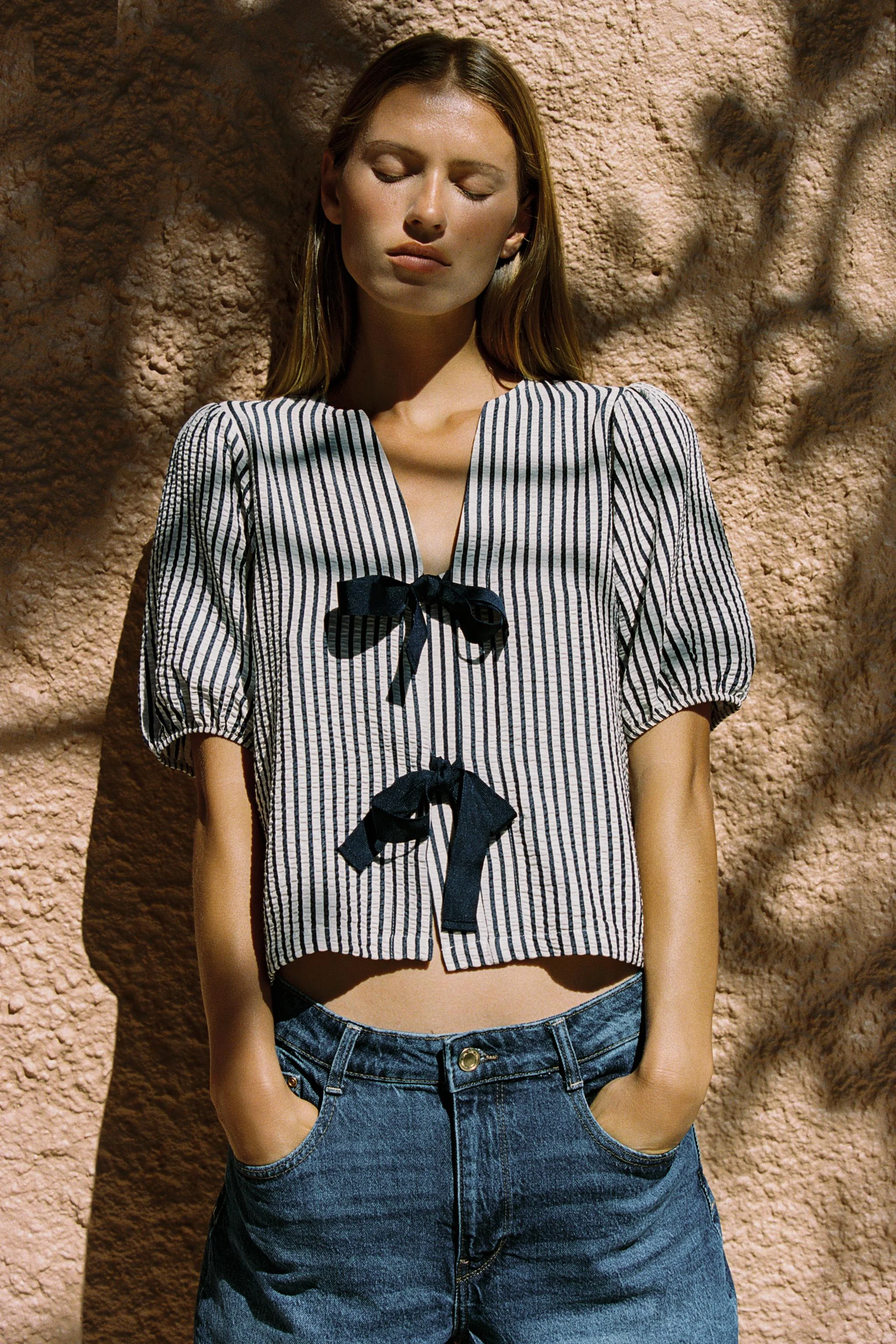 بلوز با ترکیب پارچه لینن. یقه گرد با برش هفت و آستین های کوتاه پفی با لبه کشی. دارای بند برای گره زدن در قسمت جلو.