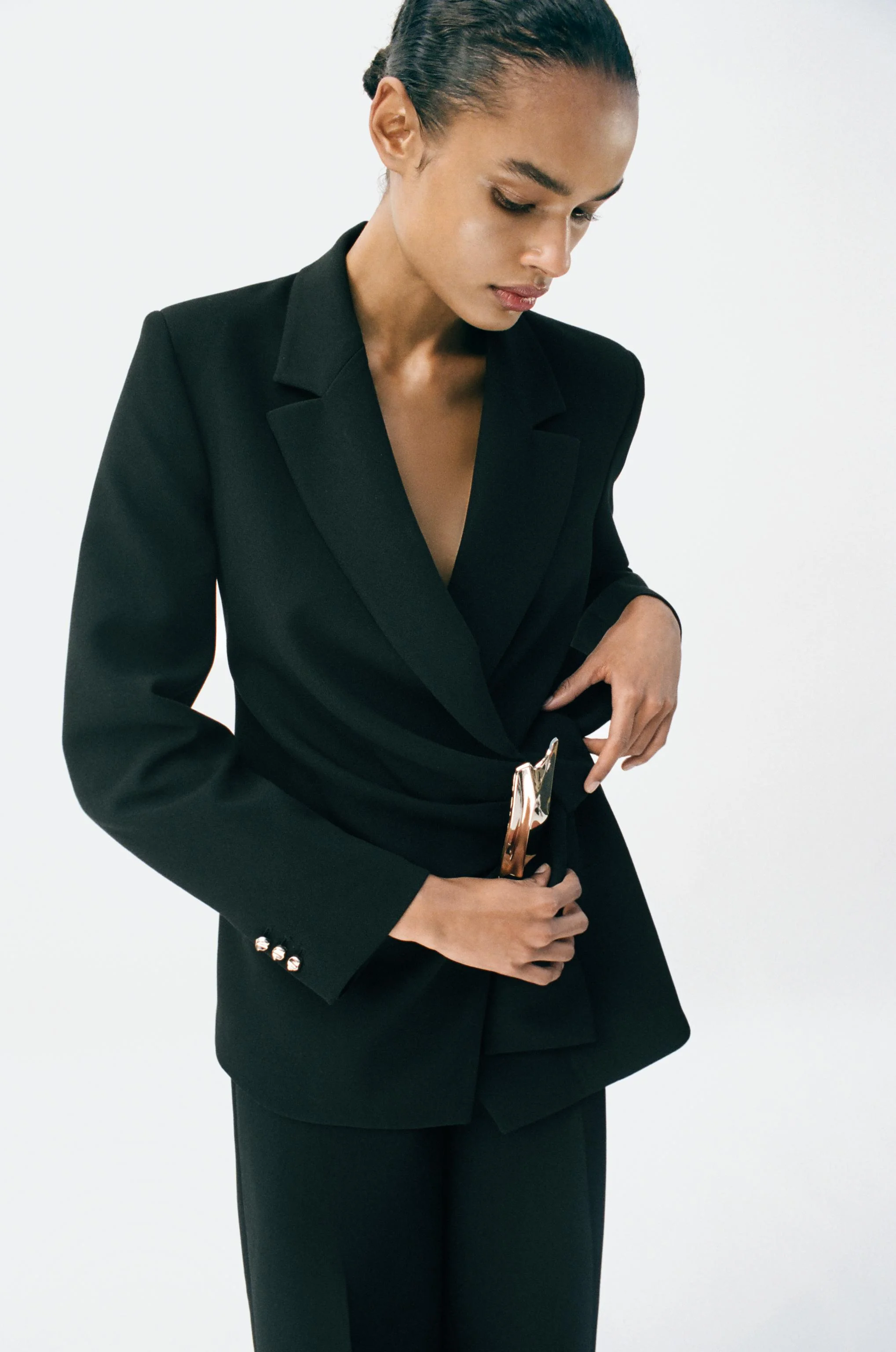 کت تک یقه برگردان آستین بلند با پد شانه. دارای سگک و گره تزئینی به همراه پلیسه در قسمت جلو. دارای بست دکمه فشاری مخفی در جلو.