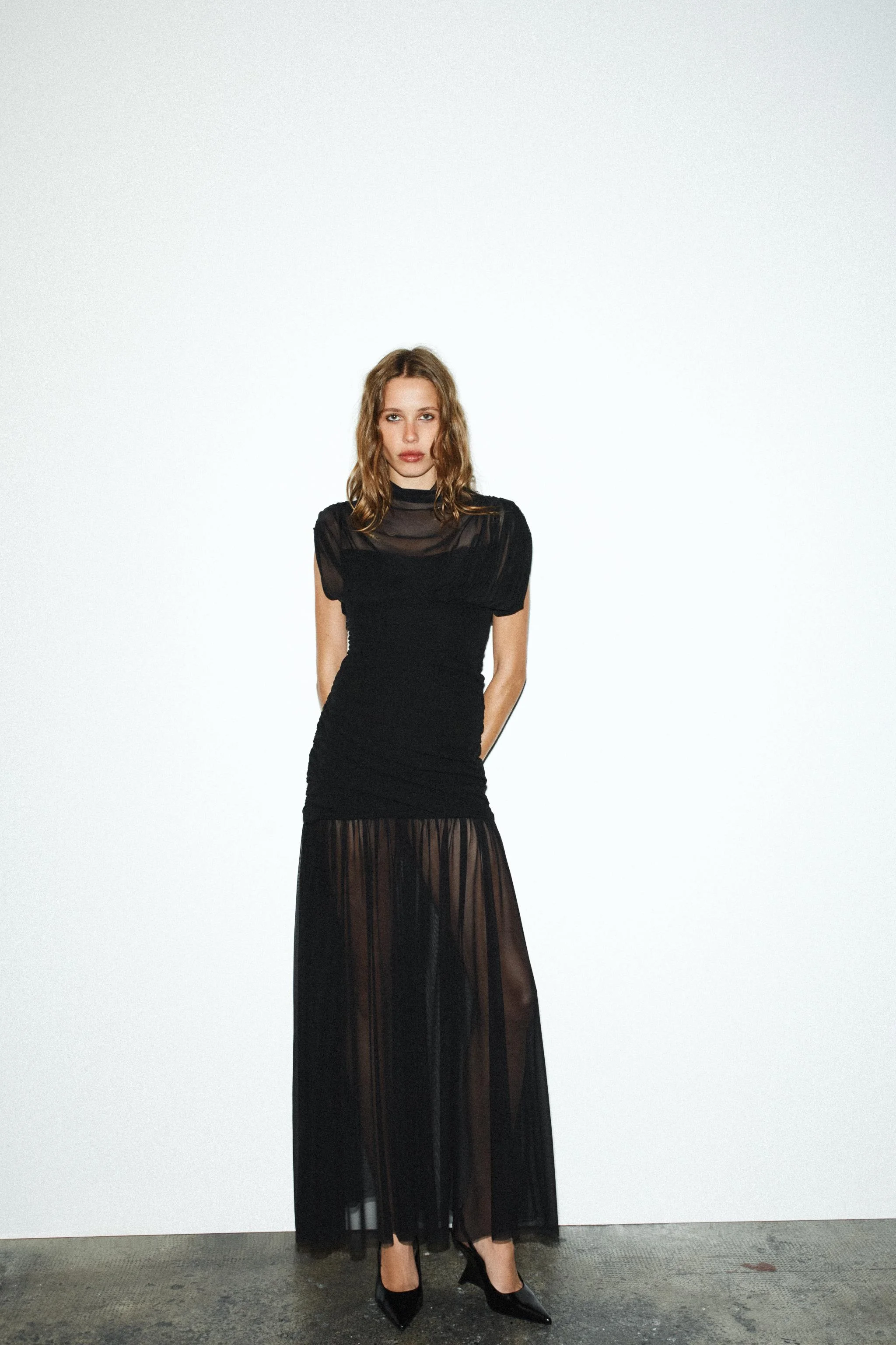 پیراهن میدی بدون آستین با یقه ایستاده و حالت دراپه. دارای آستر داخلی ترکیبی با بندهای نازک قابل تنظیم و جزئیات پارچه جمع شده. دارای زیپ نامرئی در پهلو.