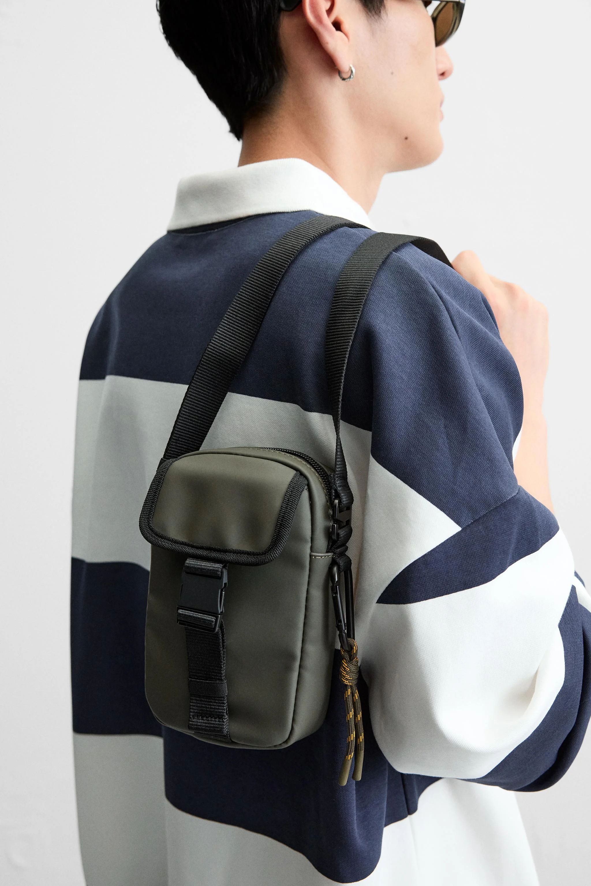 کیف رودوشی عمودی با روکش لاستیکی. دارای محفظه اصلی با زیپ. قسمت داخلی دارای یک جیب با بست صاف. قسمت جلویی دارای یک جیب با سگک بازشو سریع. بند شانه قابل تنظیم و جدا شدن. ارتفاع x طول x عرض: 18 x 11 x 5 سانتی متر.