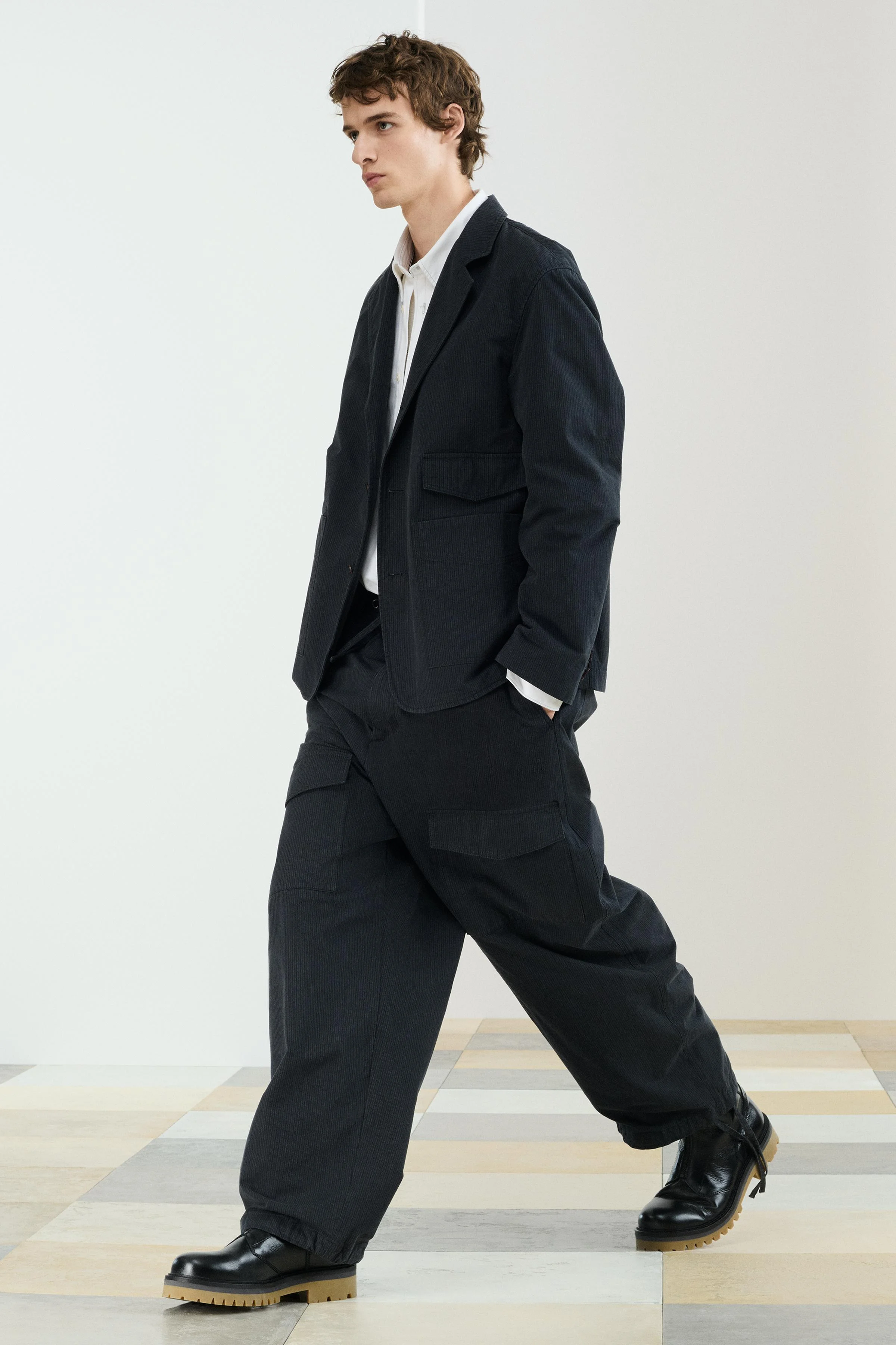 شلوار پارچه‌ای با فیت آزاد. دارای کمر کشی با بند قابل تنظیم، جیب‌های جلو و جیب‌های پشتی وصله‌ای با سرپوش. جیب‌های وصله‌ای با سرپوش روی پاها. لبه قابل تنظیم با بندهای کناری. دارای زیپ و دکمه.