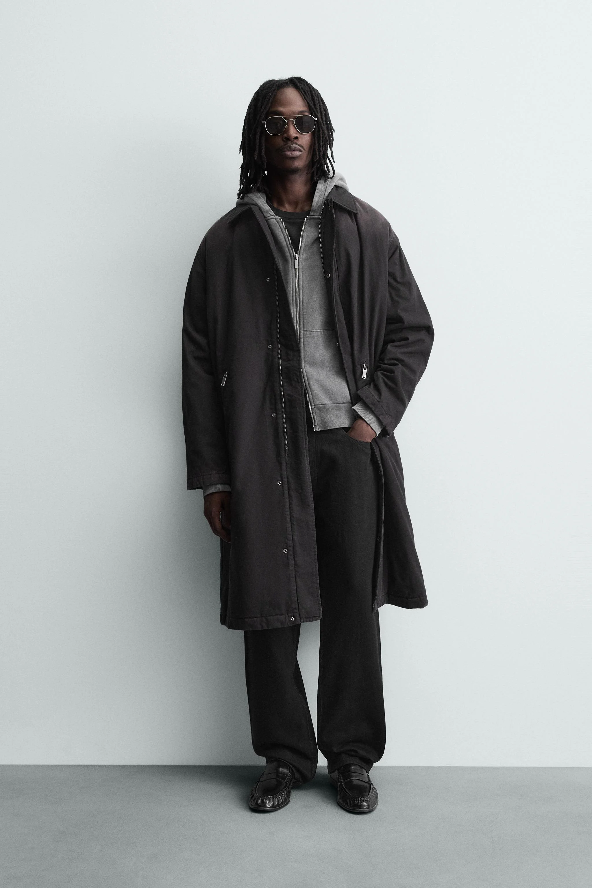 کت جین پنبه ای با تن خور راحت. دارای یقه برگردان و آستین های بلند با سرآستین های دکمه دار قابل تنظیم. دارای جیب های زیپی در قسمت جلوی باسن و یک جیب داخلی. دارای جلوه رنگ رفته. بستن جلوی کت با زیپ مخفی شده توسط یک سجاف دکمه دار.