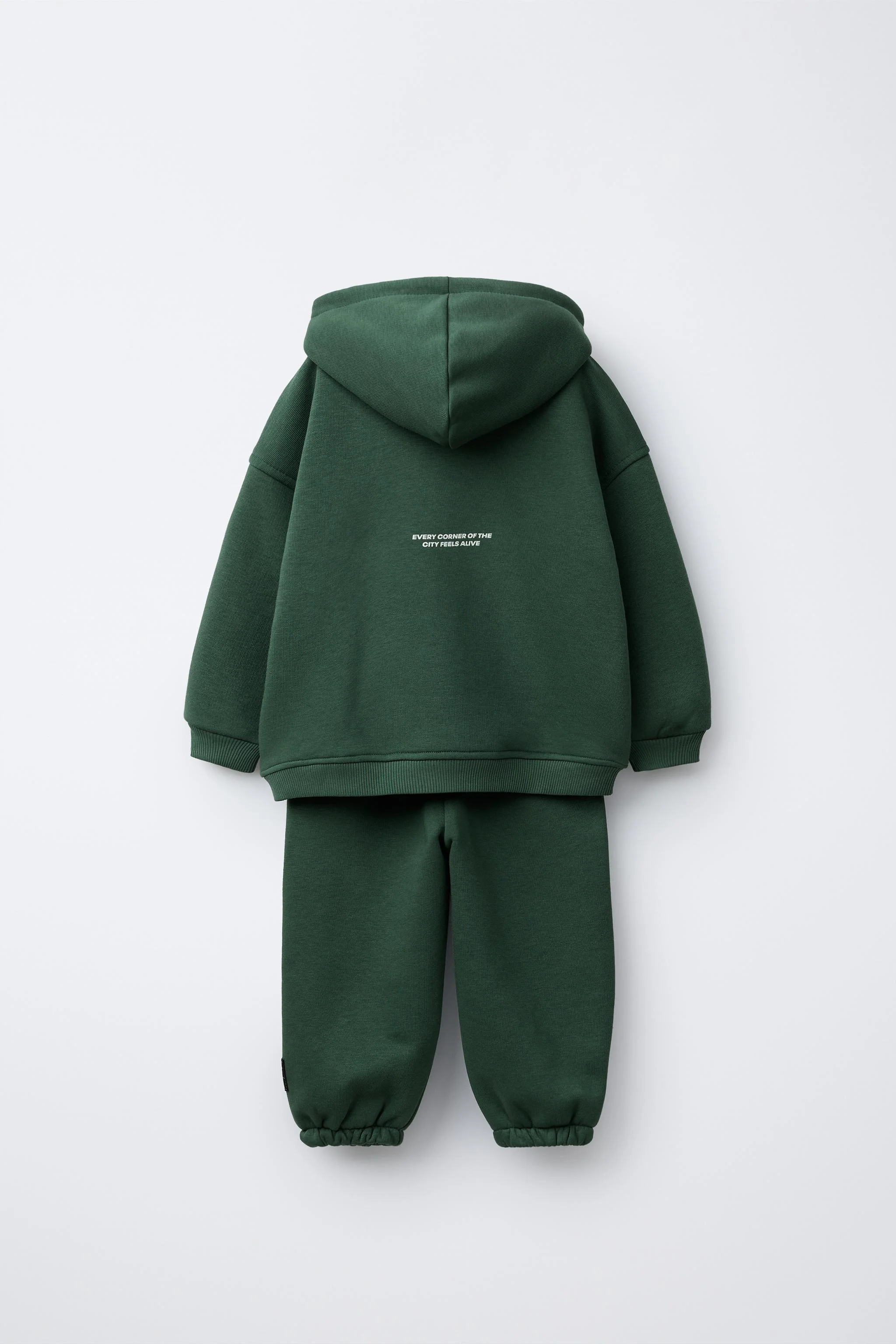 ست دو تکه جاگر. هودی آستین بلند. سرآستین های کشبافت. چاپ متن روی سینه. شلوار جاگر با کمر کشی و بند قابل تنظیم در جلو. جیب های جلو. لبه کشی. داخل نرم و گرم برس خورده. پارچه 72% پنبه.