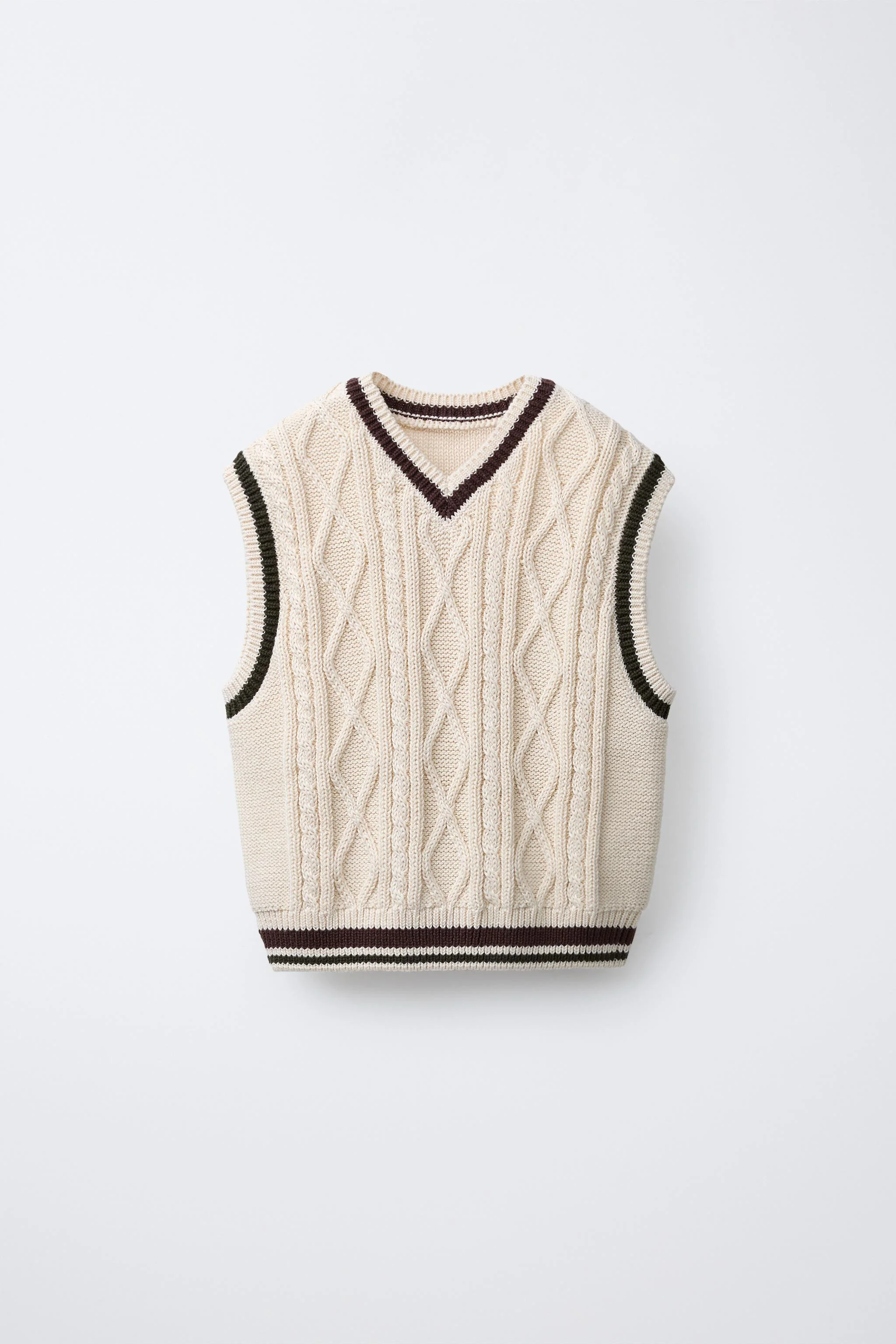 جلیقه بافتنی با طرح کابلی، یقه گرد و بدون آستین. دارای جزئیات تزیینی متضاد.