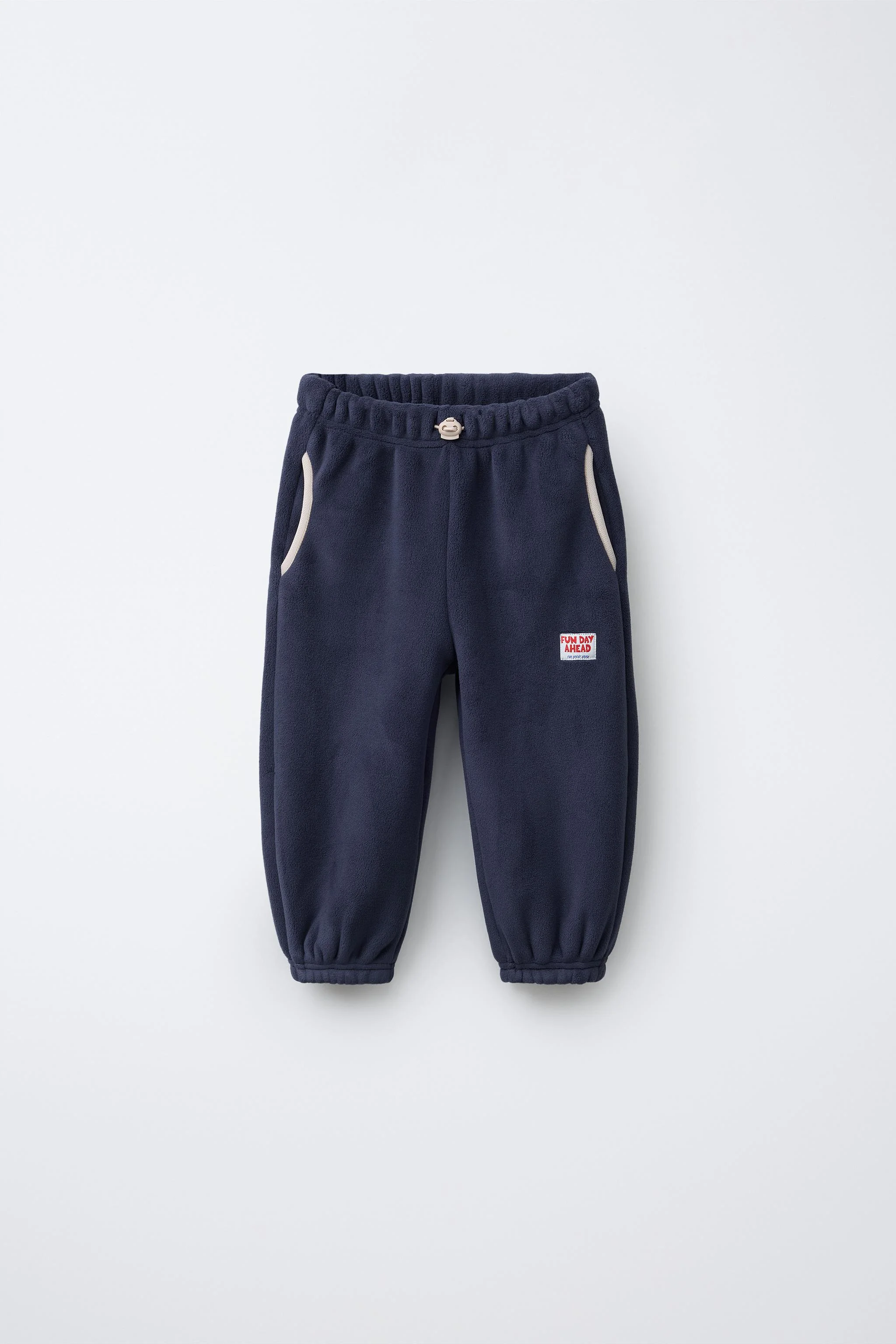 شلوار گرمکن پشمی با کمر کشی و تزئینات استاپر در جلو. دارای جیب های جلو با جزئیات ولت و یک تکه برچسب در جلو.