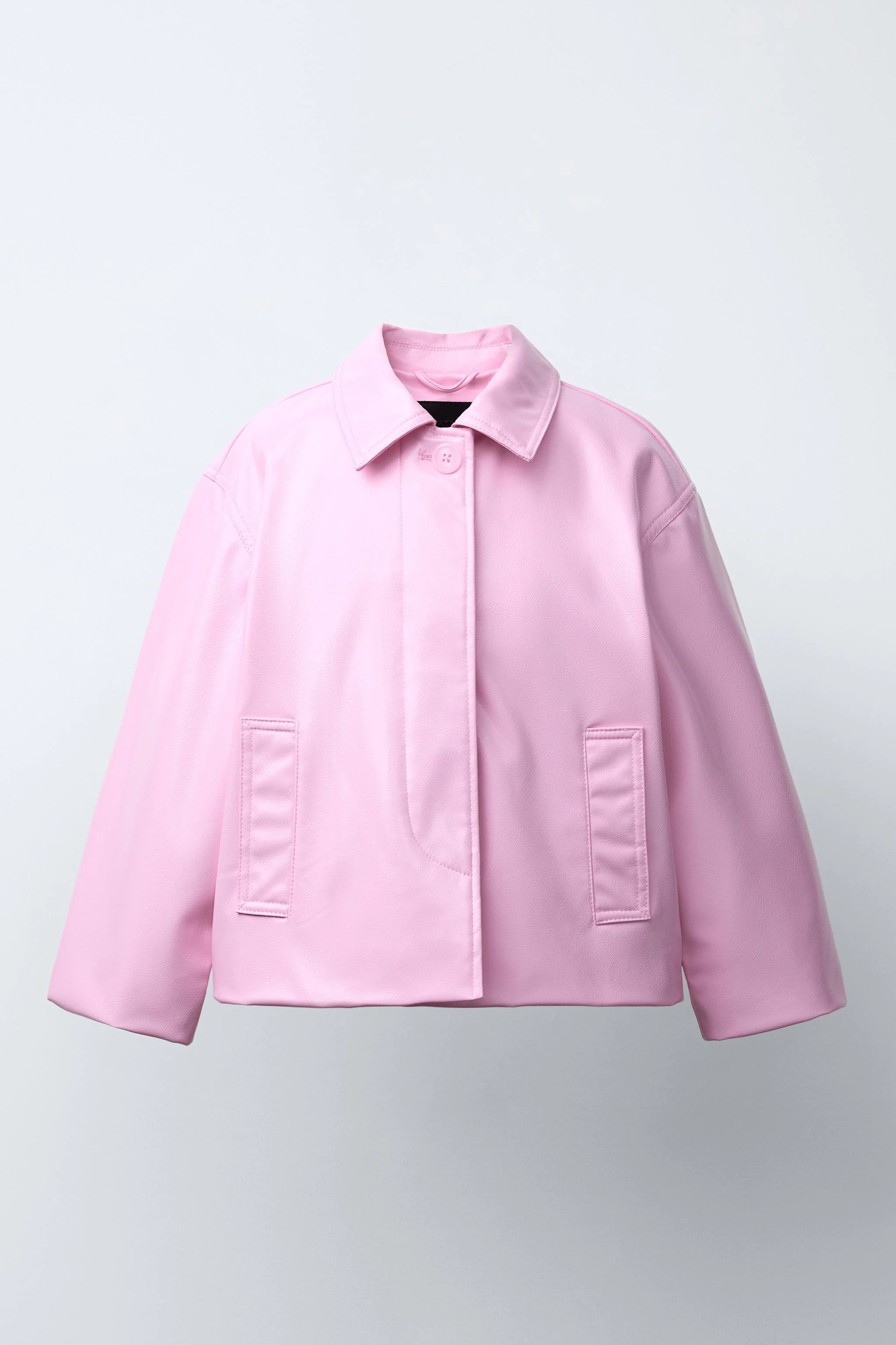 کت با طرح چرم، دارای یقه پیراهنی و آستین بلند. دارای بست دکمه ای مخفی در پشت یک سجاف جلویی و جیب های جلویی با جزئیات لوله کشی.