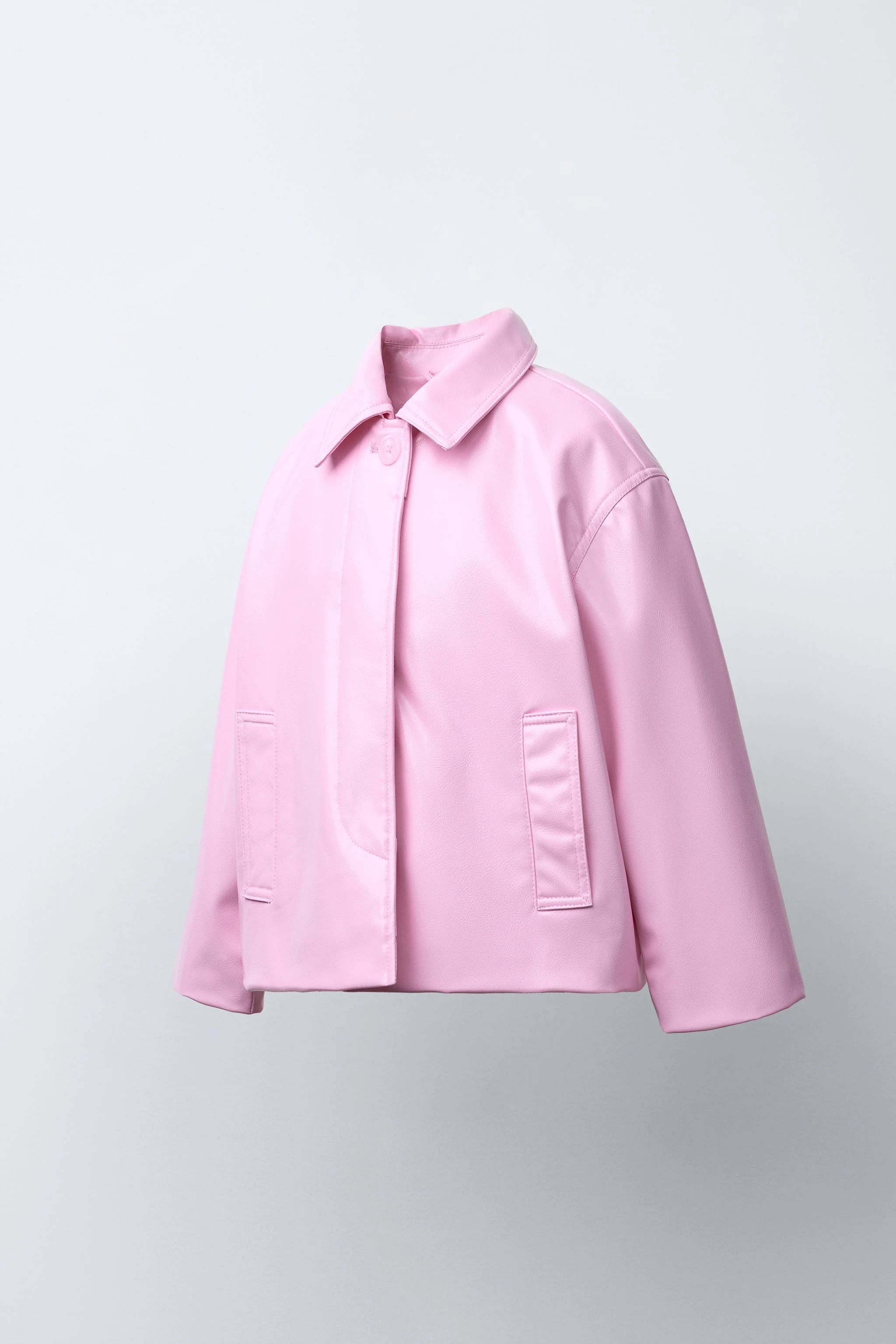 کت با طرح چرم، دارای یقه پیراهنی و آستین بلند. دارای بست دکمه ای مخفی در پشت یک سجاف جلویی و جیب های جلویی با جزئیات لوله کشی.