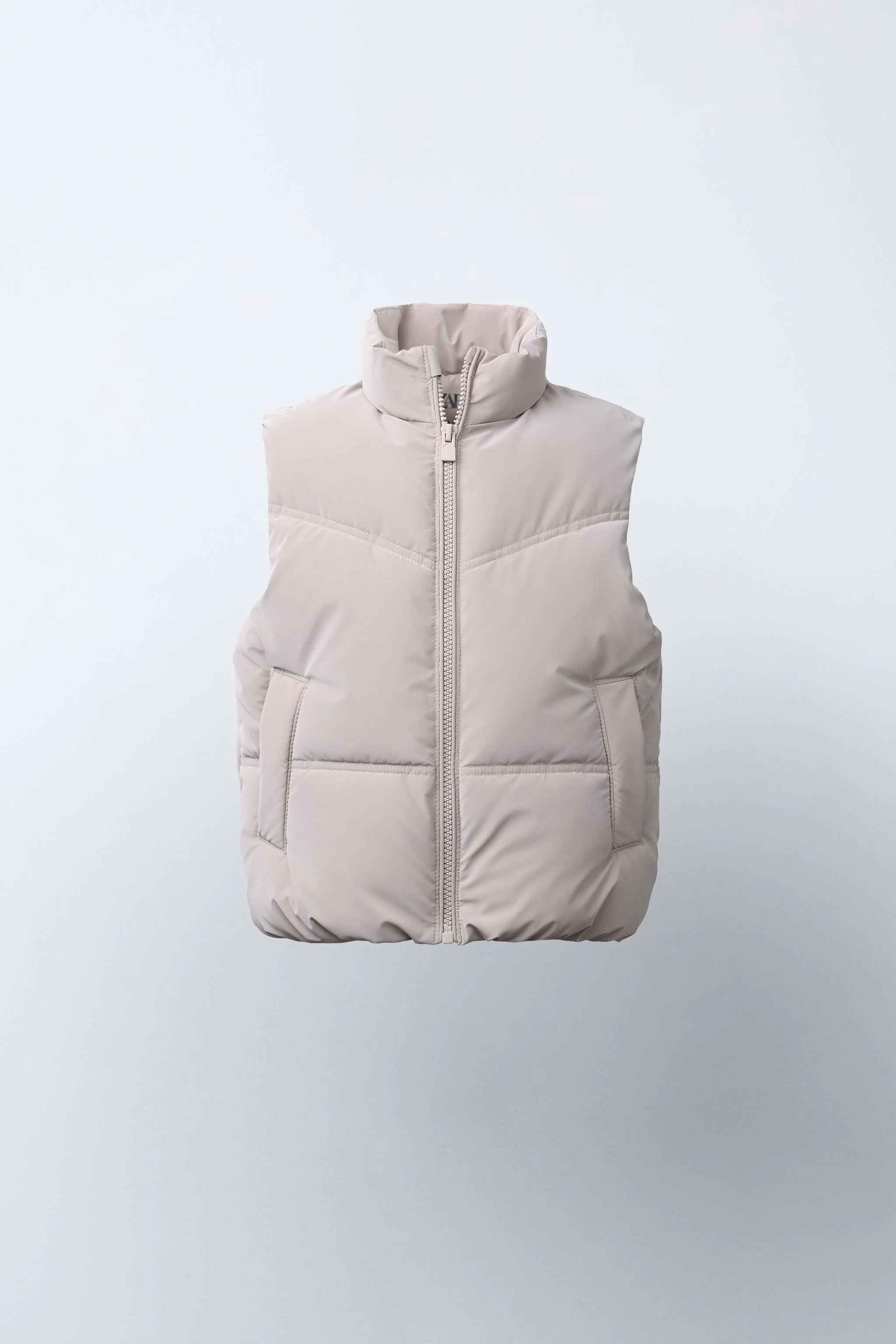 جلیقه بدون آستین با یقه ایستاده. دارای زیپ در جلو و جیب های جلویی با جزئیات لبه دار.