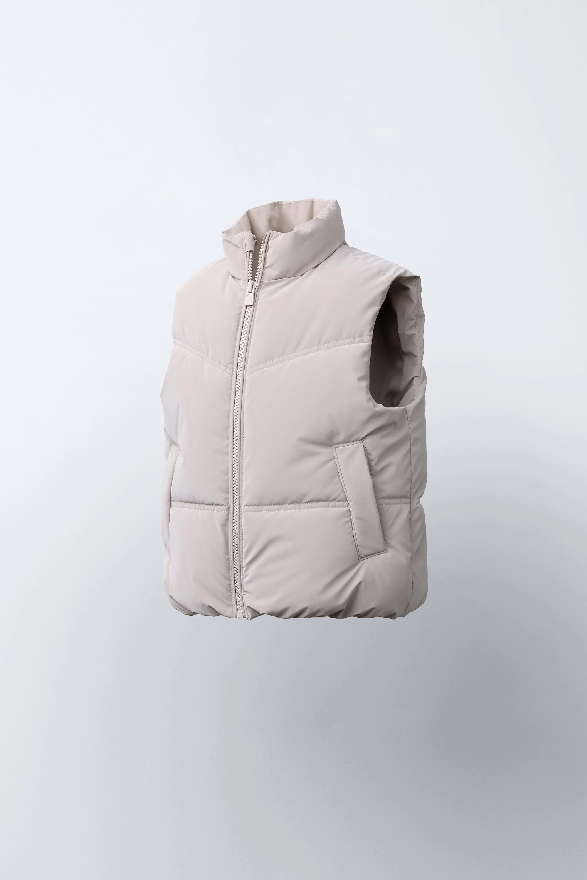 جلیقه بدون آستین با یقه ایستاده. دارای زیپ در جلو و جیب های جلویی با جزئیات لبه دار.